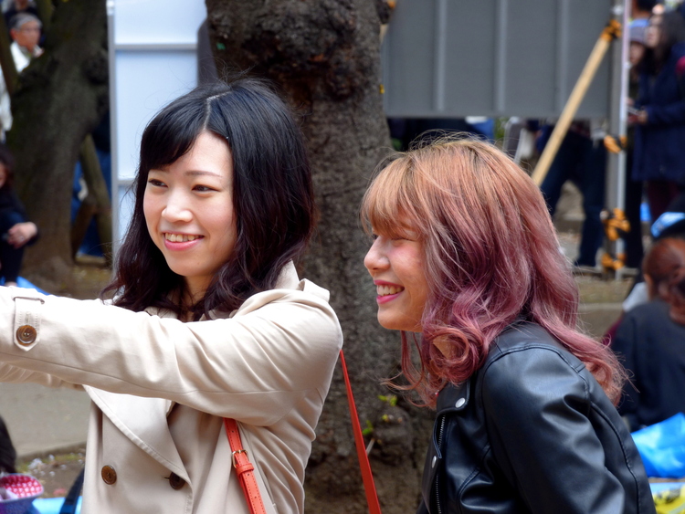 Two young women, one with orange-violet hair, taking selfies