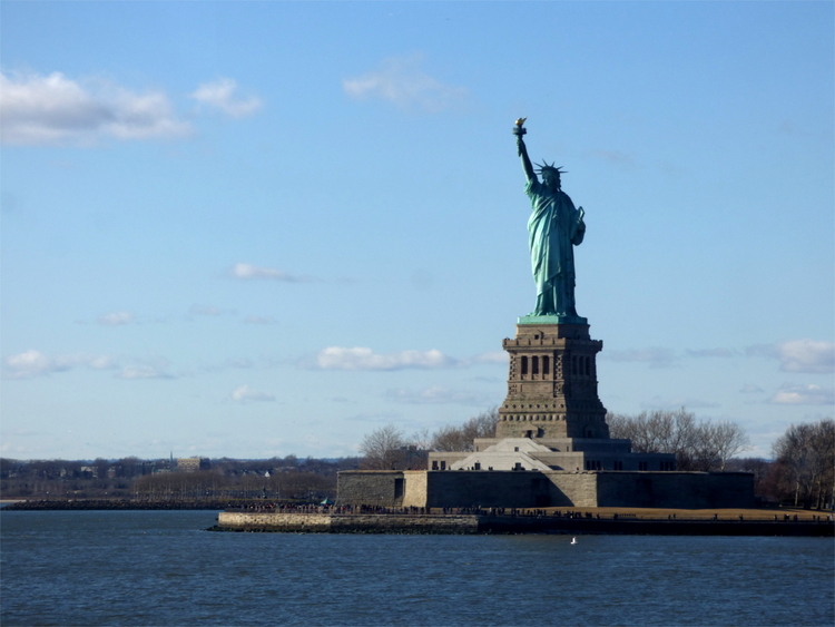 The statue of liberty standing on her pedestal on a small island