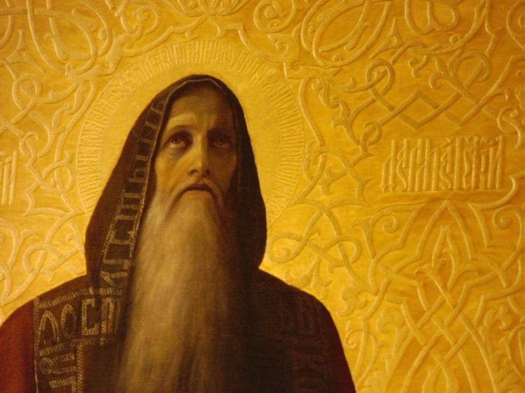 Close-up of a religious artwork showing an old man with a long white beard in an ornamented red hood looking up to the sky in front of an ornamental plate-gold background