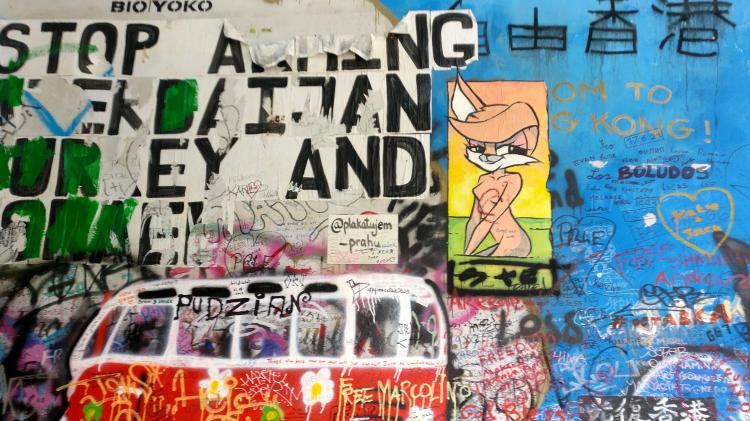 A wall covered in graffiti and tags with political messages, including several in support of Hong Kong; also comic-style art of an anthropomorphized fox