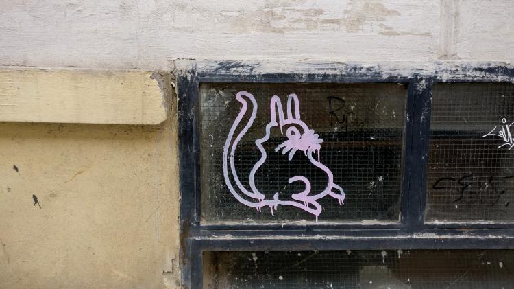 A line-drawing of a plump pink rabbit or cat creature on a cellar window