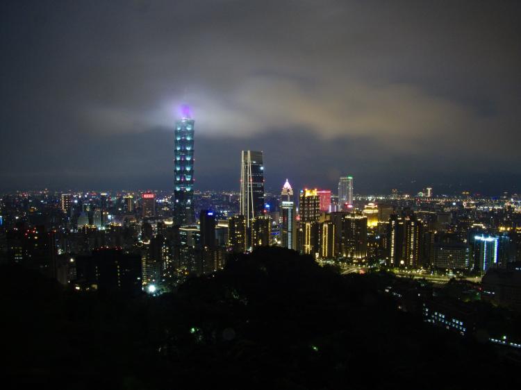 The skyline of Taipei with the Taipei 101 skyscraper piercing through the low clouds at night