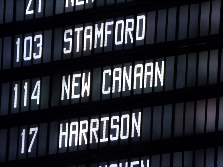 Close-up of the departures display on a train station, showing the lines '103 Stamford', '114 New Canaan' and '17 Harrison' in a blocky white font