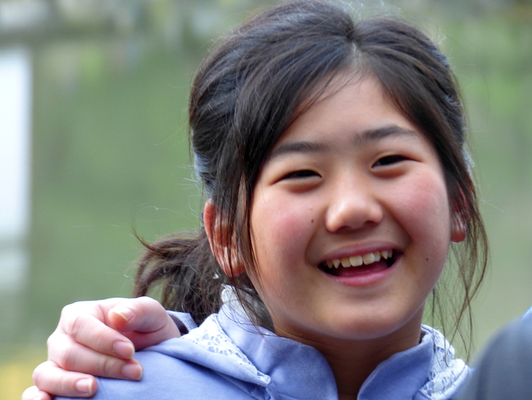 A young girl smiling widely, posing for a picture