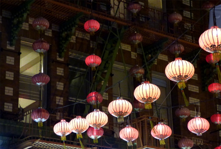 Chinese red lanterns hanging across the street from a red brick facade