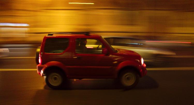 A red SUV driving along a street