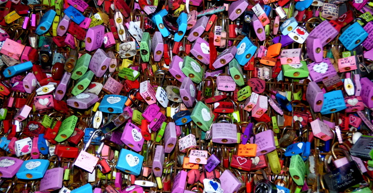 Hundreds of love-locks in all shapes and colours with names and messages inscribed on them locked on a metal grate.