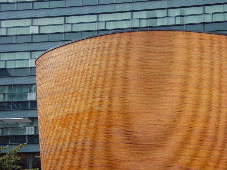 A featureless, oval building with a facade made from copper-coloured metal strings