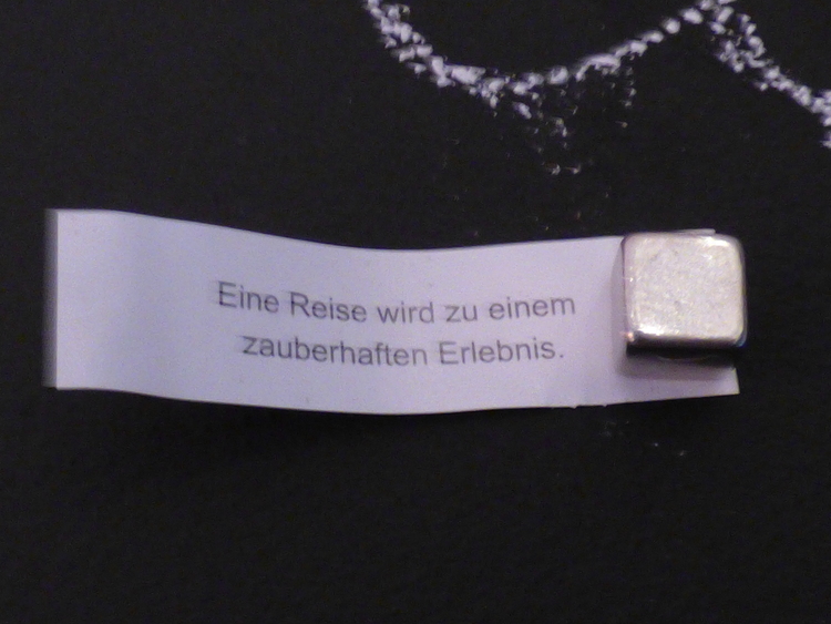 A fortune cookie fortune reading 'A journey will be a magical experience' in German