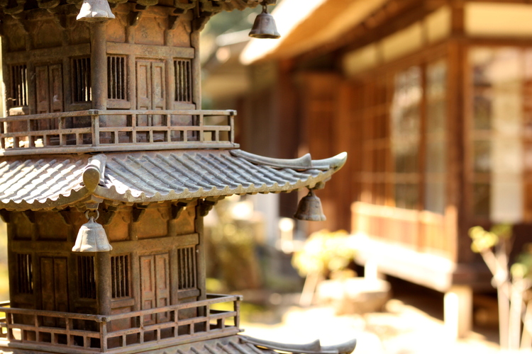 Close-up of a miniature pagoda in front of a traditional wooden Japanese building
