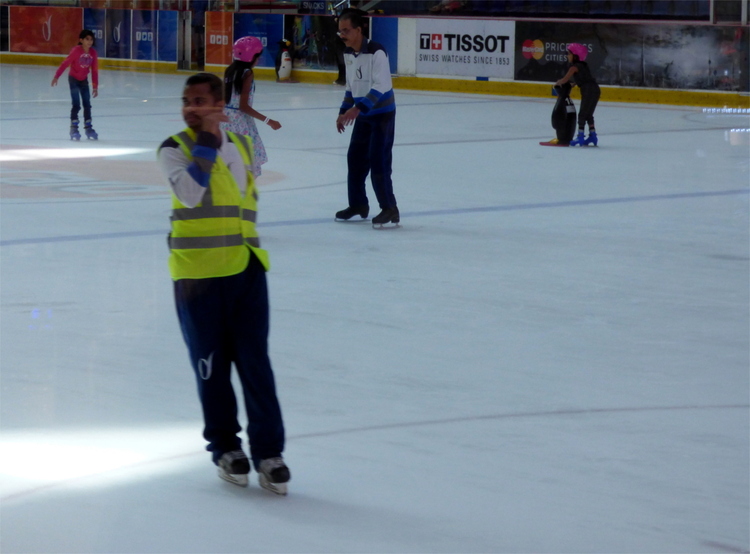 A mall security officer in a high-vis vest ice-skating on an indoor rink