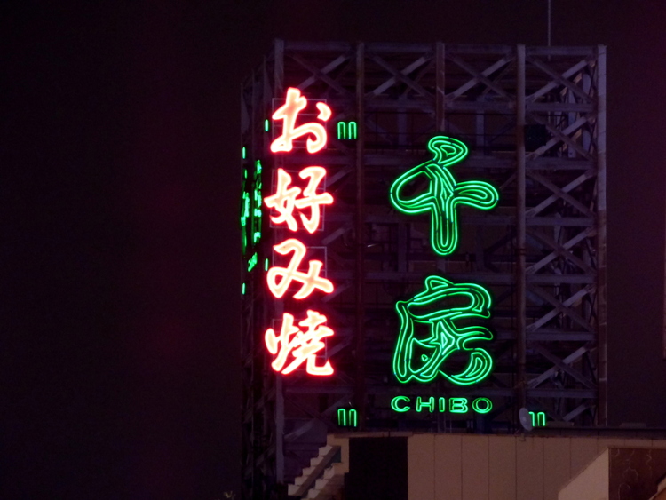 A neon sign of green and red Japanese characters