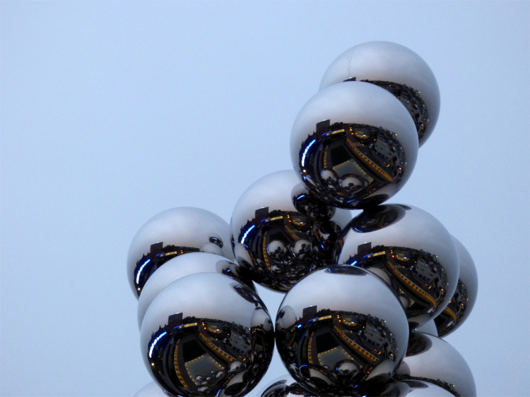 A sculpture of large, reflective metal balls stacked on top of each other