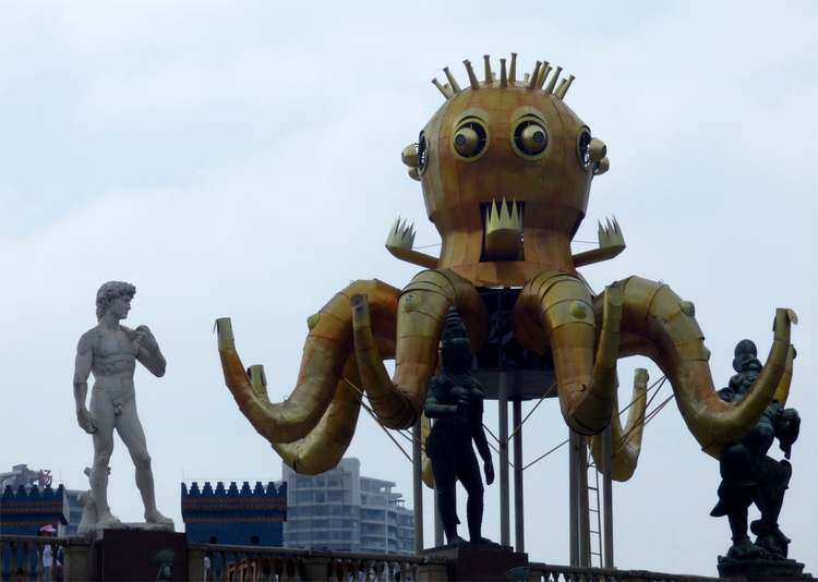 A copy of Michelangelo's David standing next to a larger brass-coloured metal octopus