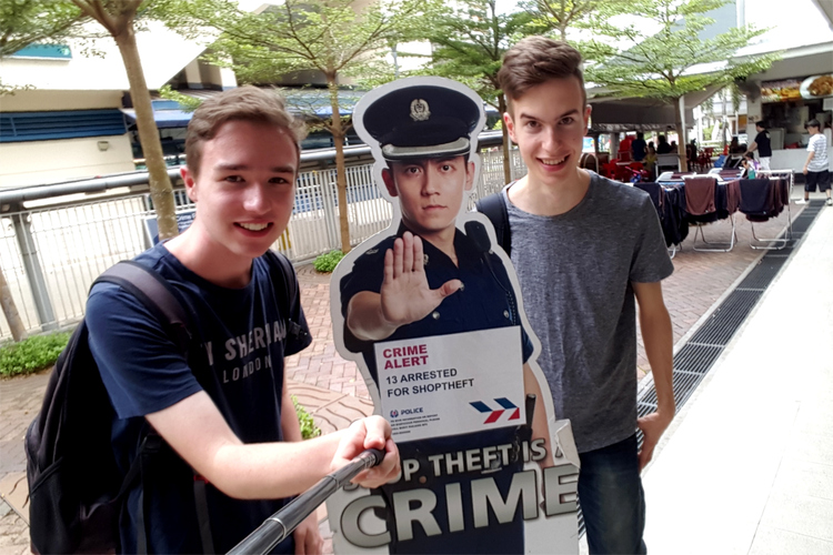 Jan and Nils posing next to a paper cut-out of a policeman making a 'stop' gesture, informing about shoplifting