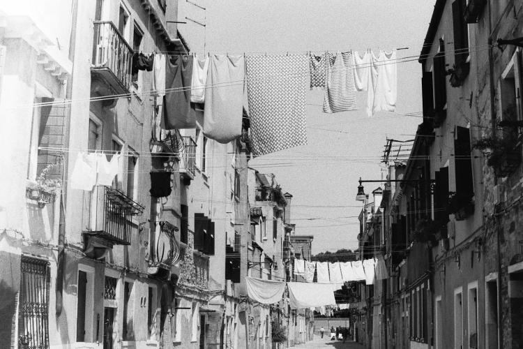 Laundry suspended on washing lines over a wide pedestrian street between two rows of houses