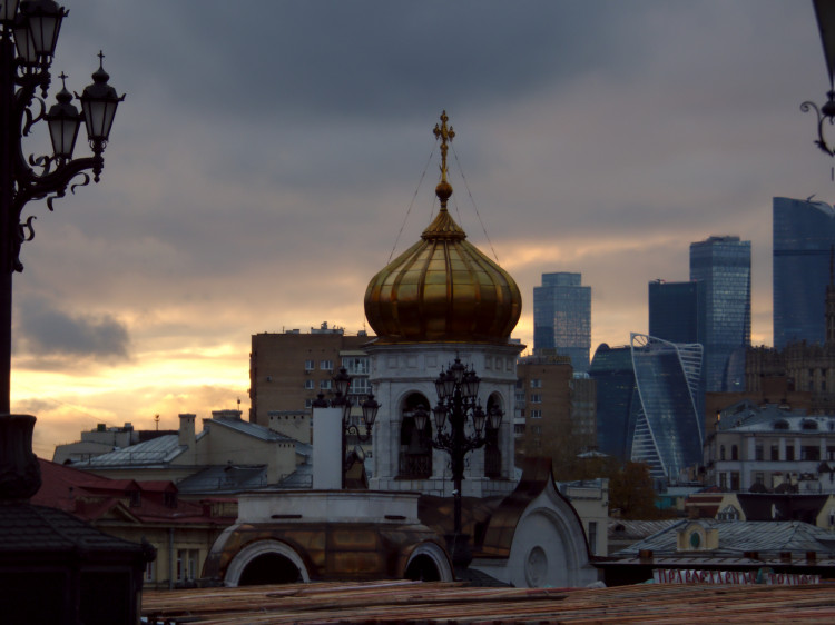 A view of the Moscow skyline at sunset with a golden domed building in the center