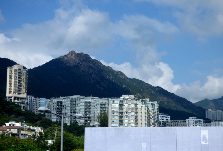 A view showing grey high-rise residential buildings in front of a mountain ridge