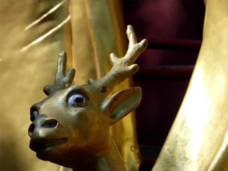 The head of a golden statue depicting a surprised-looking deer