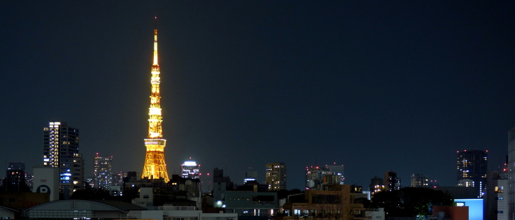The yellow-lit Tokyo Tower emerging from the rooftops at night