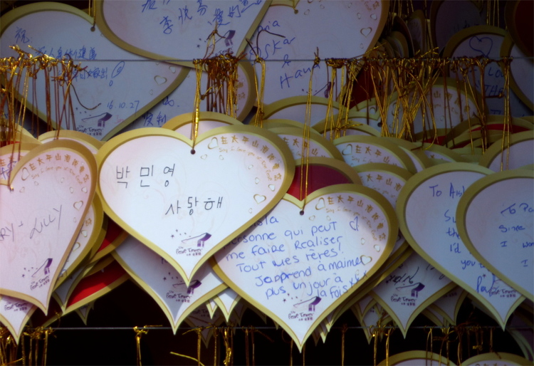 Many paper hearts with hand-written messages in various languages, one of them in poorly written Korean