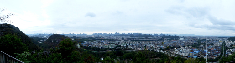 Panorama of a city of low, grey-ish buildings under a cloudy sky