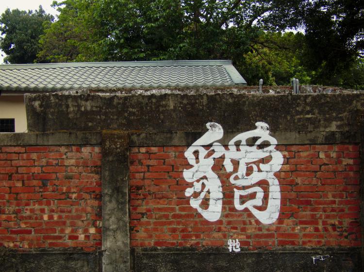 A Chinese character artfully painted in white on a brick wall