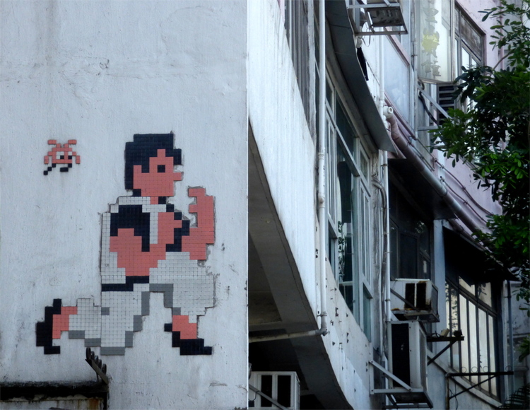 Mosaic-tile street-art showing a pixelated martial arts fighters on a building wall