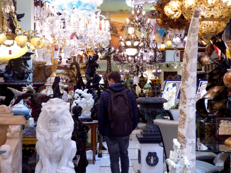 Jan entering an antiques store full of various sculptures and chandeliers