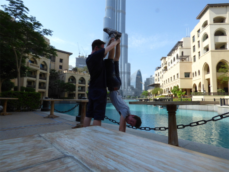 Jan holding Nils doing a handstand in front of the Burji Khalifa