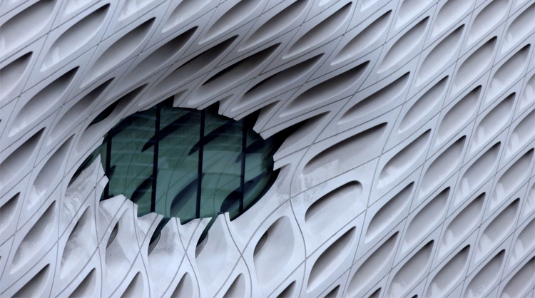 An organic-looking futuristic facade made of white plastic with many holes in it and an oval shaped window looking like an eye