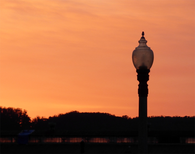 A glass street lantern against a vibrant orange and red sunset sky