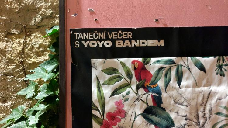 The upper corner of a poster showing a retro tropical motive and the text 'tanecni vecer s yoyo bandem'