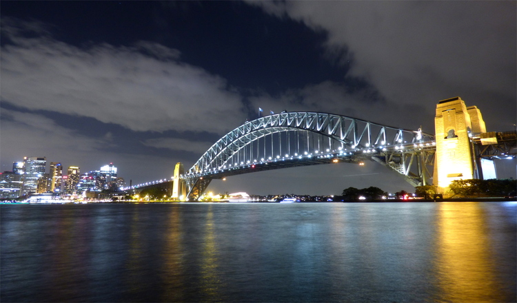 The Sydney harbour bridge, an arched steel construction, lit up at night