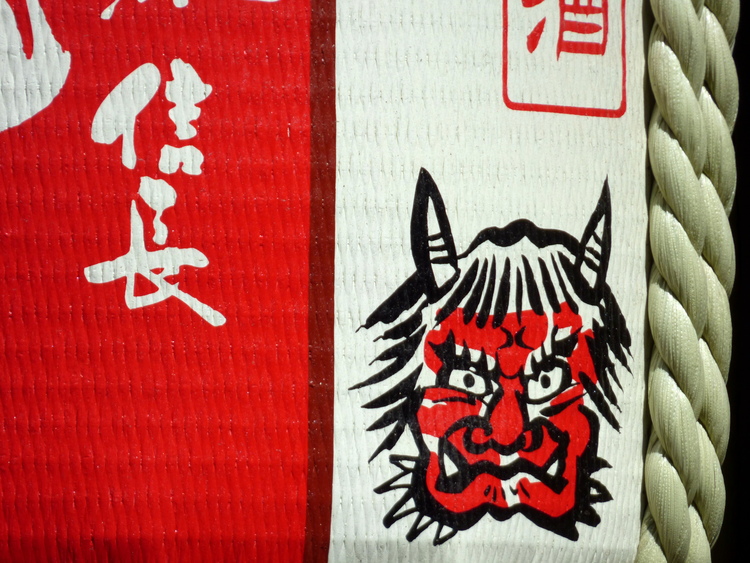 Close-up of a sake barrel with a red-and-black drawing of a devil's face