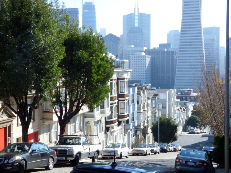View of a steep San Francisco street with some high-rise buildings in the background