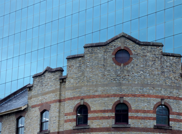 An old red brick facade meeting a modern blue glass buildingfront
