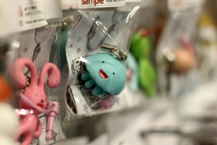 Close-up of key fobs shaped like an excited blue jellyfish and a scared-looking pink bunny on a shelf wrapped in plastic