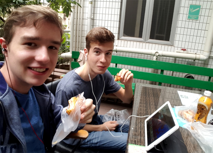 Jan and Nils having breakfast outside while watching something on a tablet computer