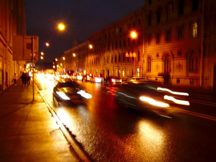 Blurry photo of cars driving down a wide street at night
