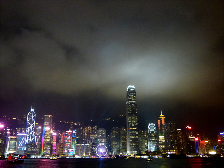 Skyscrapers of the lit-up Hong Kong skyline underneath a cloudy night sky