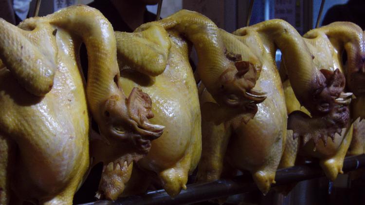 Featherless whole raw chickens with unnaturally bent necks lined up at a restaurant