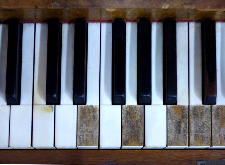 Close-up of a well-worn piano keyboard in a wooden frame