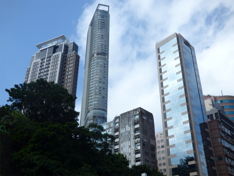 Various grey, glass-clad skyscrapers with trees in the foreground