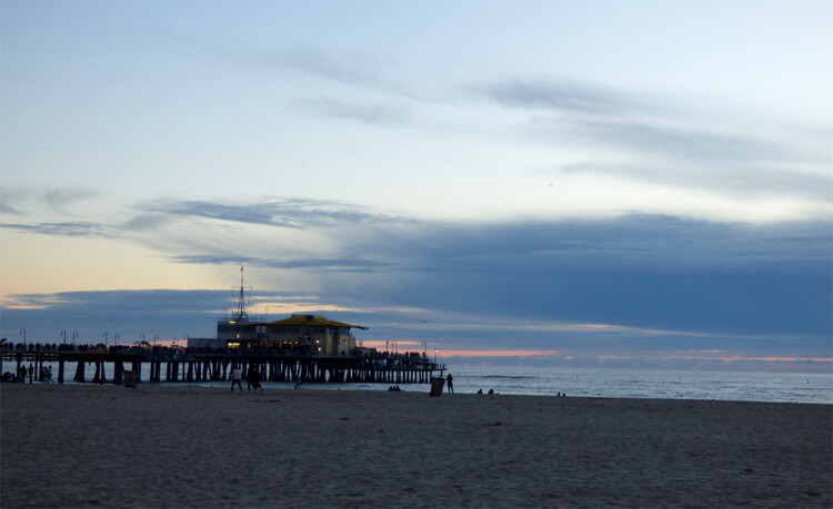 A small house in the distance on a wooden pier on a sandy beach