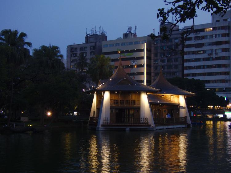A small pavilion on a lake in a public park at night 