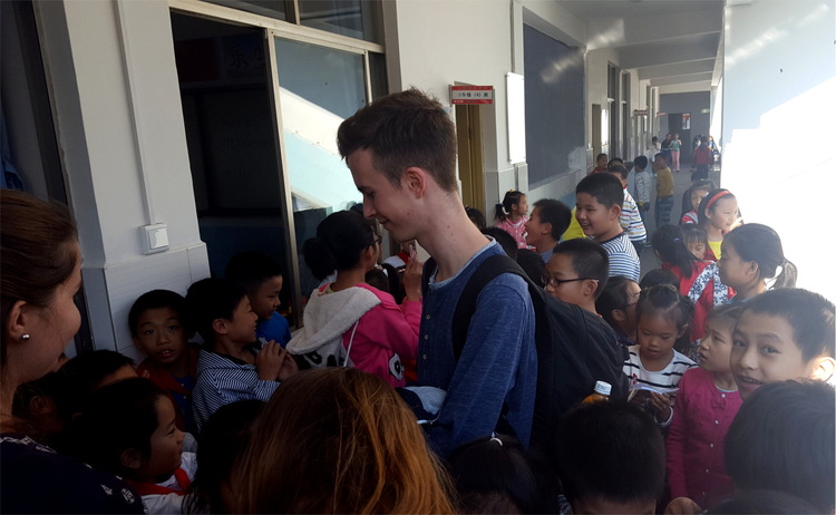 Nils standing in a crowd of elementary school children in a corridor asking for autographs
