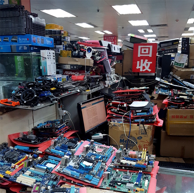 A market booth overloaded with boxes full of mainboards and other computer components