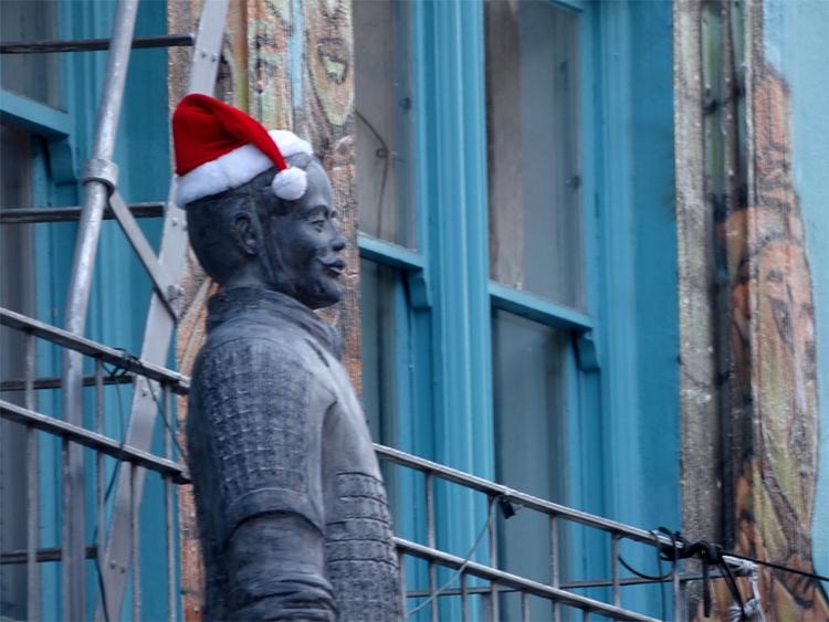 A statue of a Chinese warrior wearing a red-and-white Santa hat