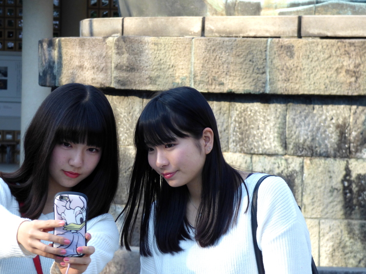 Two young women taking selfies together, one holding a phone with a Minnie Mouse case